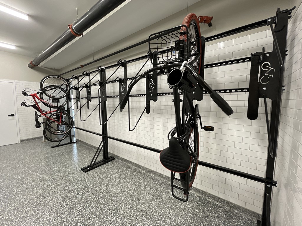 a workout room with bikes hanging on the wall and weights on a rack