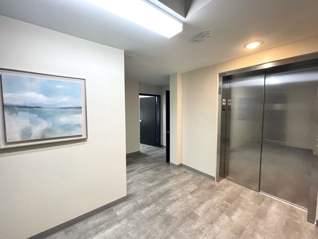 A hallway with a painting on the wall and a glass door.