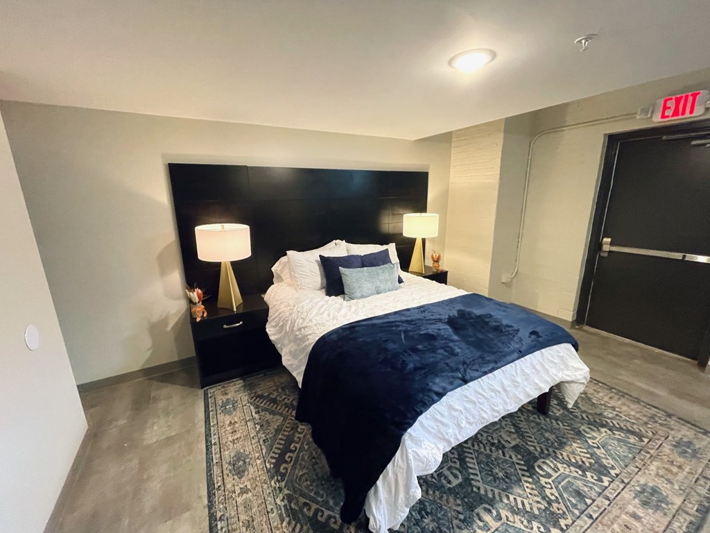 A bedroom with a large bed and a rug on the floor.