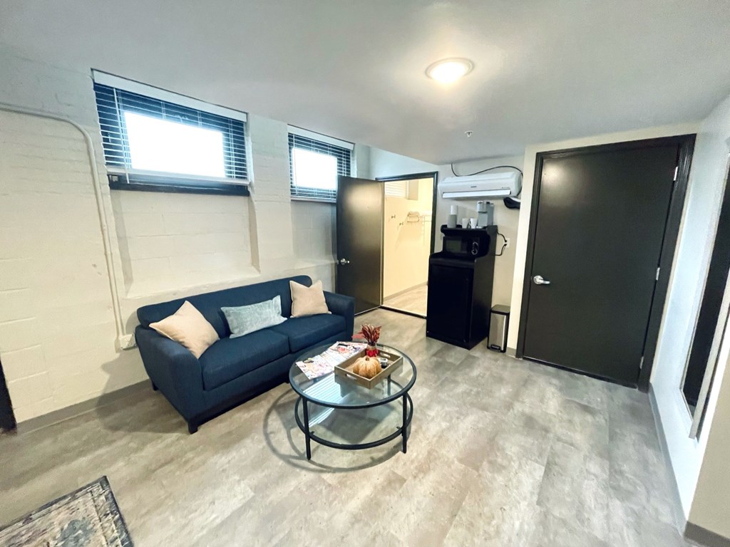 A living room with a blue couch and a glass coffee table.