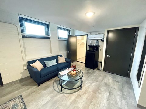 A living room with a blue couch and a glass coffee table.
