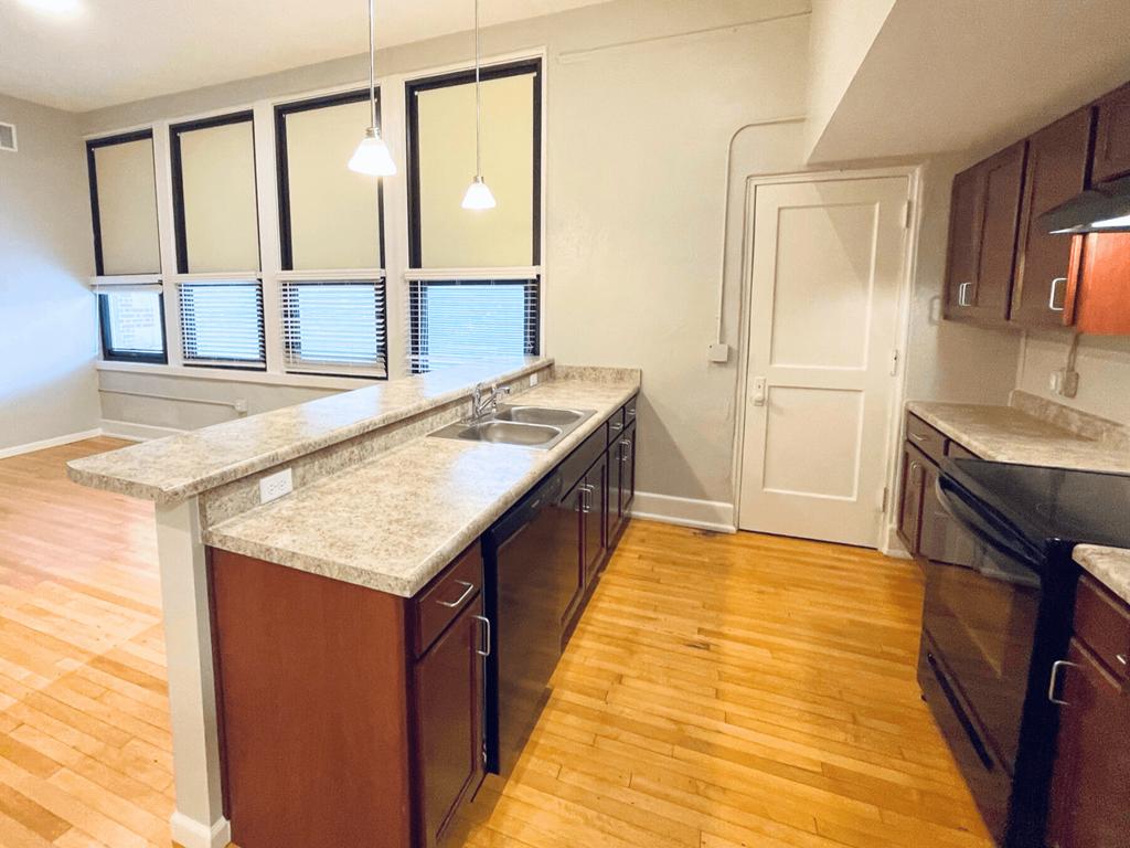 A kitchen with wooden floors and a marble countertop.