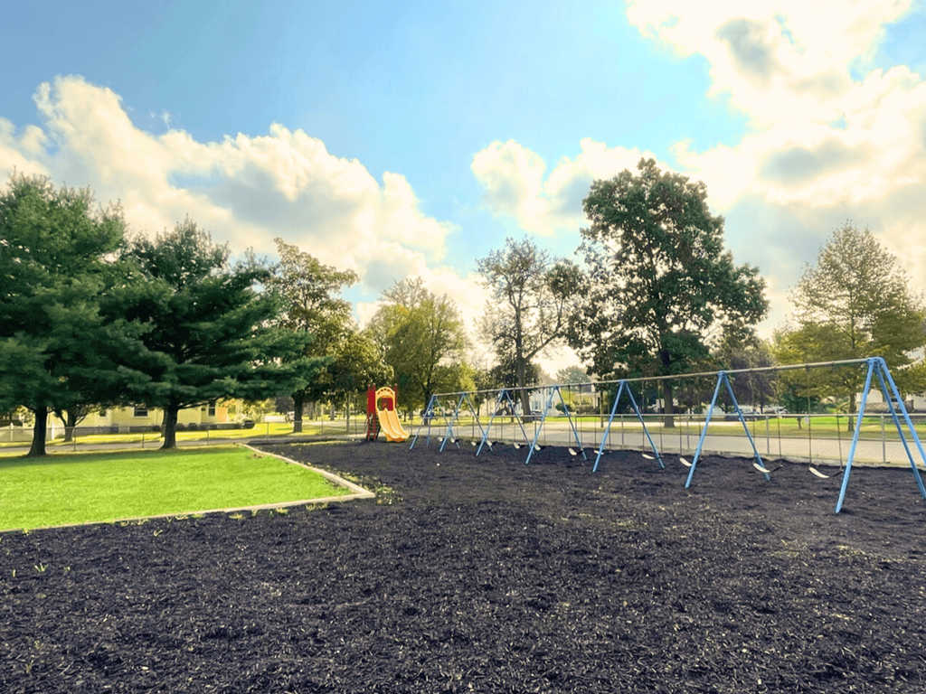 A playground with a slide and swings in a park.
