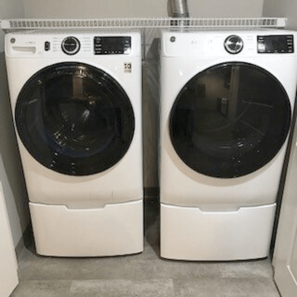 Two white front loading washing machines in a laundry room.