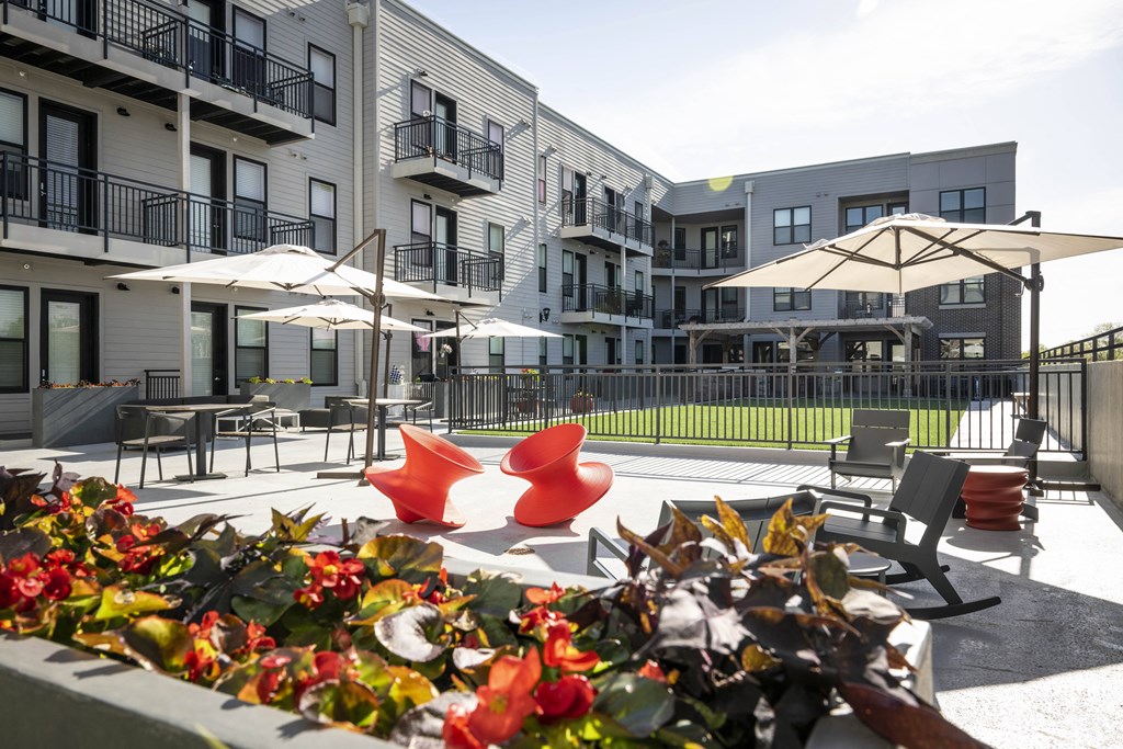 an outdoor patio with chairs and umbrellas in front of an apartment building