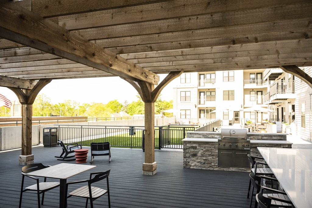 a covered patio with tables and chairs and a grill