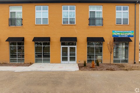 A building with a blue sign that says "NOW LEASING" is shown.