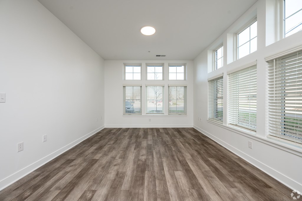 A room with wooden flooring and large windows.