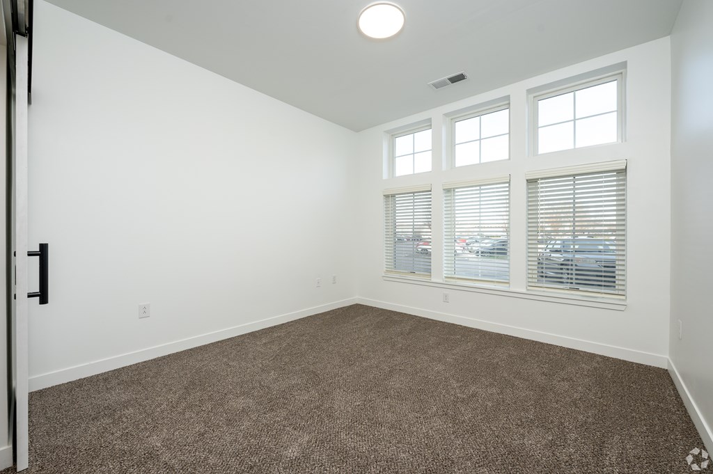 A room with a carpeted floor and a window with blinds.