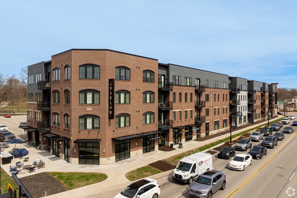 A street view of a row of modern buildings with cars parked in front.