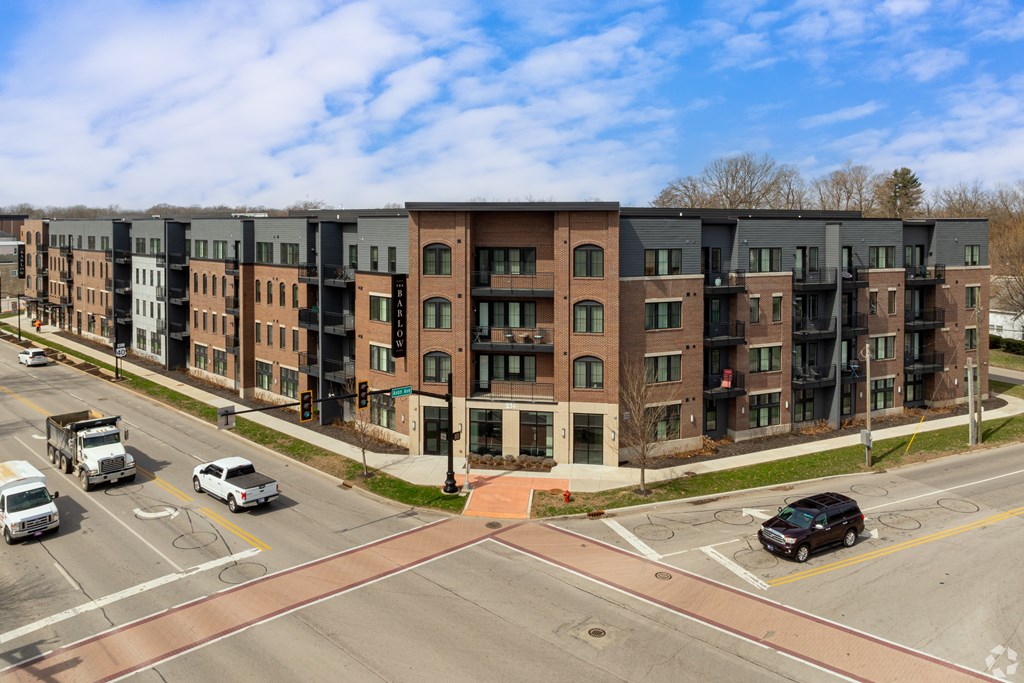 A street view of a row of apartment buildings with cars parked on the street.