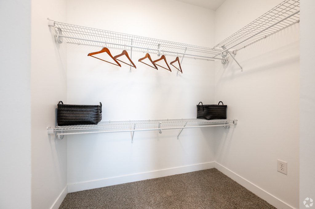 A white wall with a metal rack and two black bags.