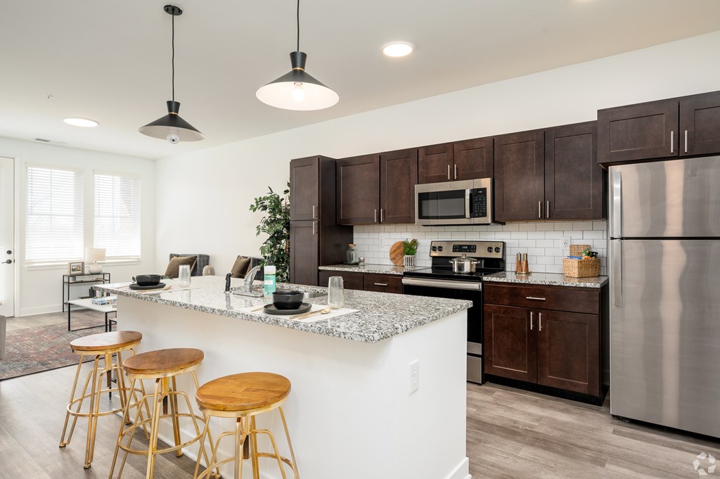 A kitchen with a white island and wooden stools.