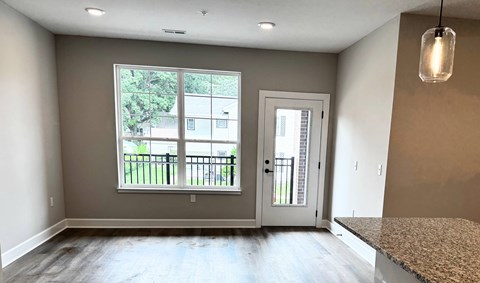 A room with a large window and a door leading to a balcony.