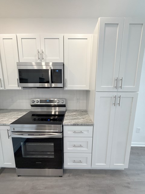 A kitchen with white cabinets and a black stove top oven.