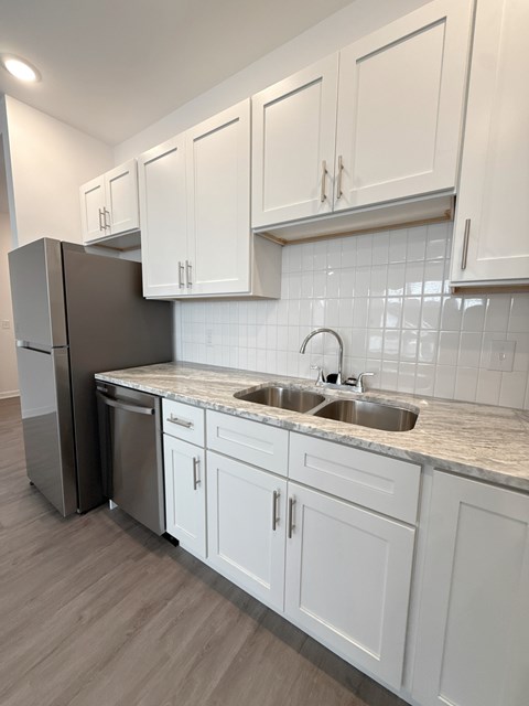 A kitchen with white cabinets and a marble countertop.
