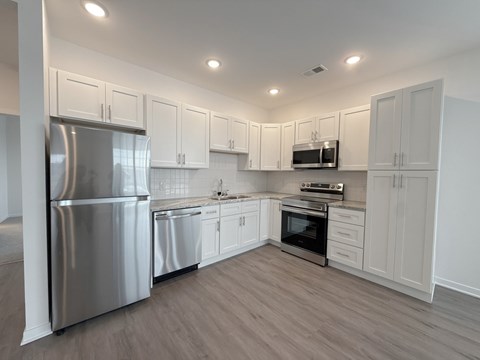 A modern kitchen with white cabinets and stainless steel appliances.