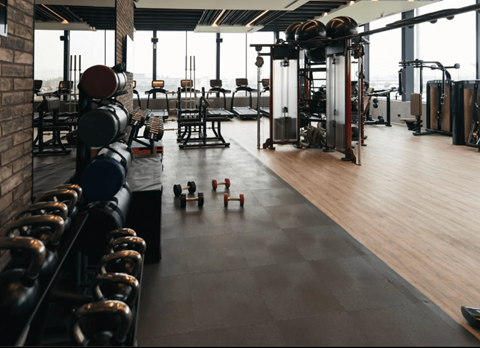 A gym with a variety of equipment including dumbbells, weight plates, and a squat rack.