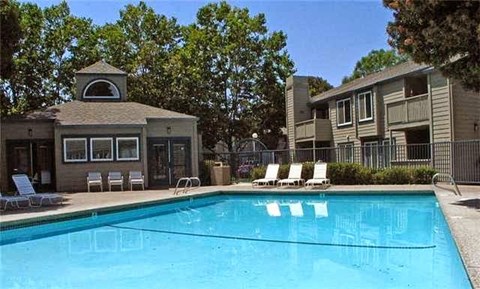 A swimming pool in front of a building with a gazebo.