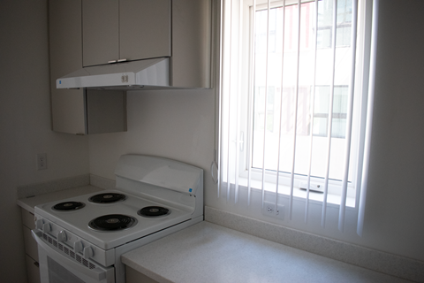 A white stove in a kitchen with a window.