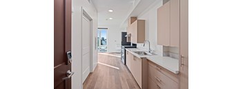 A modern kitchen with wooden floors and a white countertop.