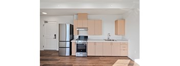 A kitchen with a refrigerator, oven, and sink.