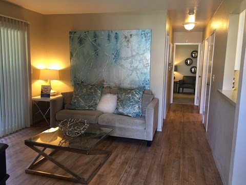 A living room with a grey couch and a glass coffee table.
