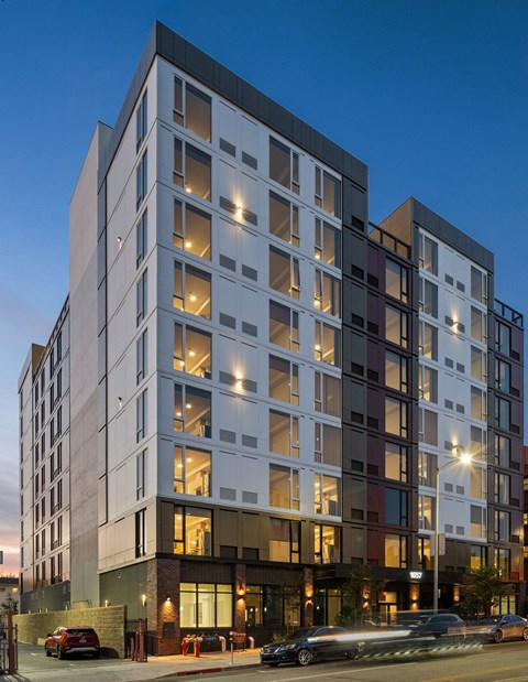 A modern multi-story building with a lot of windows and lights on.
