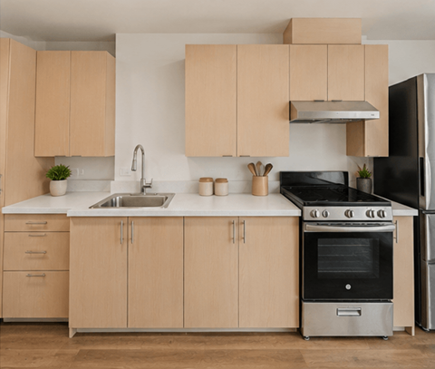 A kitchen with wooden cabinets and a black refrigerator.