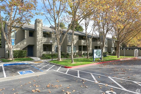 A parking lot in front of a building with a blue sign on the left.