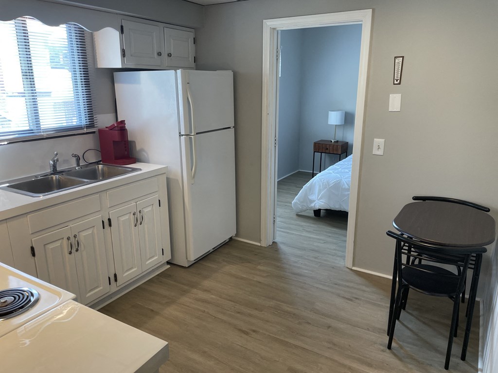 a kitchen and a bedroom with a refrigerator and a sink