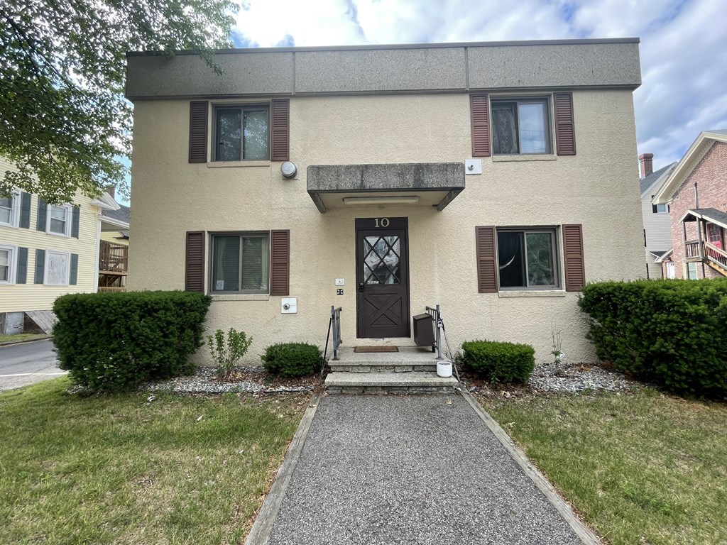 a white house with a black door and a sidewalk in front of a lawn