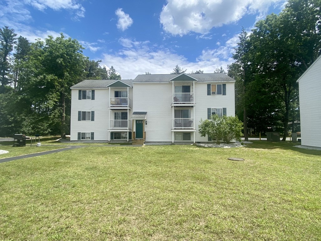 a large lawn in front of a white apartment building