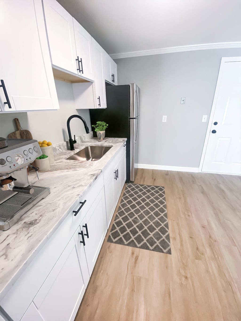 a kitchen with white cabinets and a black refrigerator