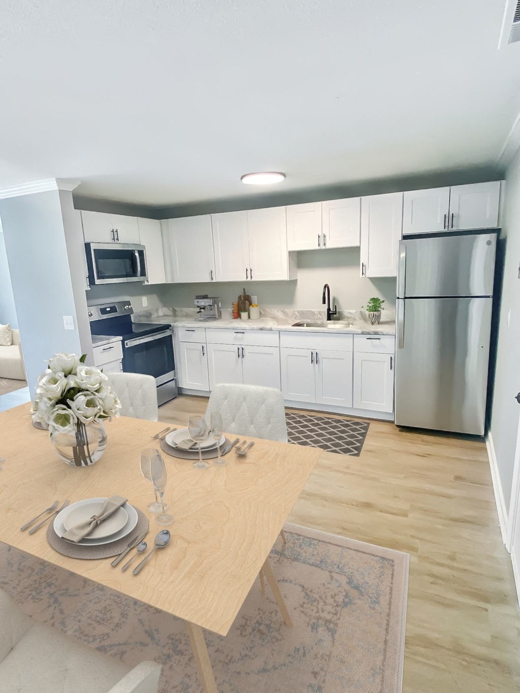 a kitchen and dining room with white cabinets and stainless steel appliances