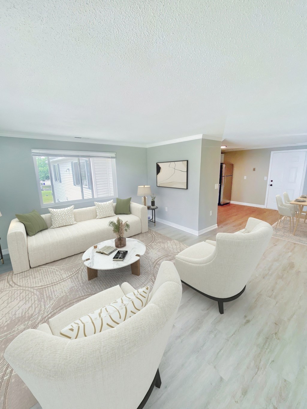 a living room with white couches and chairs and a rug