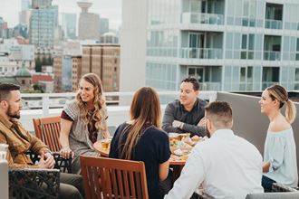 a group of people sitting around a table on a rooftop patio