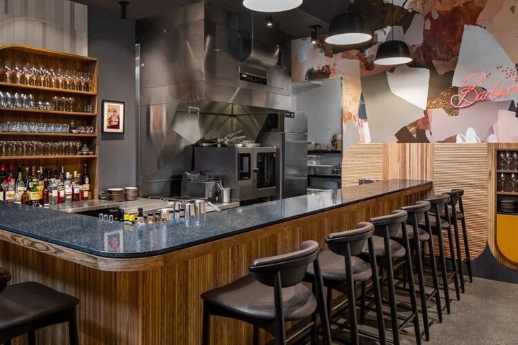 a bar in a restaurant with a kitchen in the background