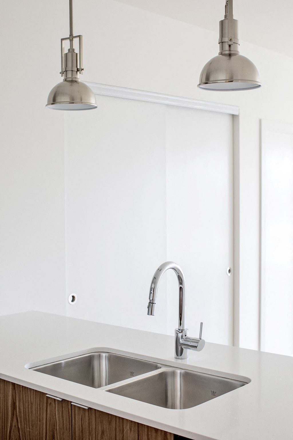 a kitchen sink in front of a mirror and two lights