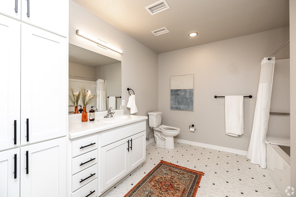 A bathroom with a white toilet, sink, and cabinets.