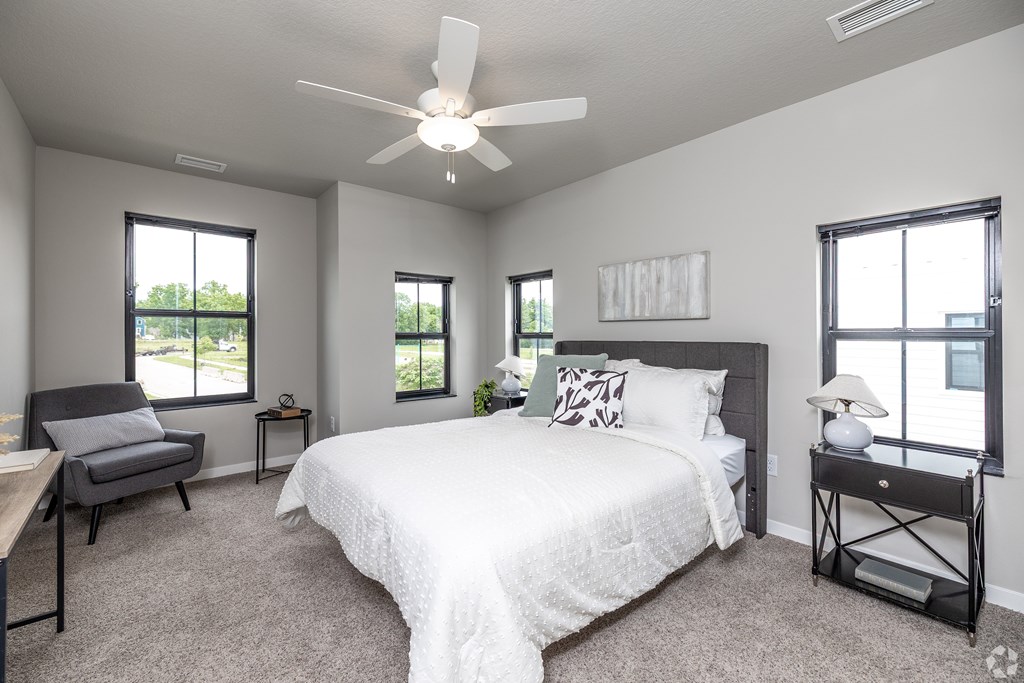 A bedroom with a large bed, a chair, and a ceiling fan.