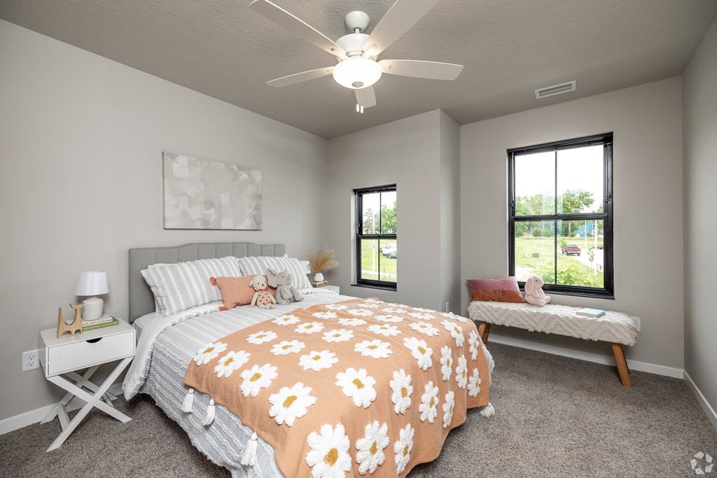 A bedroom with a bed, bench, and window.