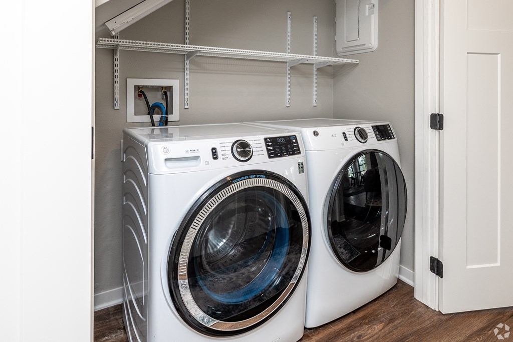 Two white front load washing machines in a laundry room.