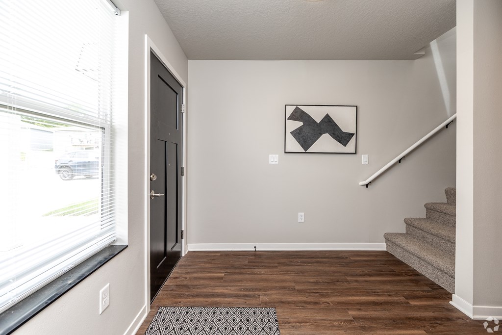 A hallway with a wooden floor and a staircase.