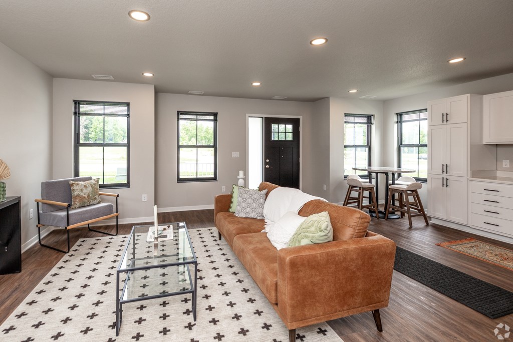 A living room with a brown couch and a glass coffee table.