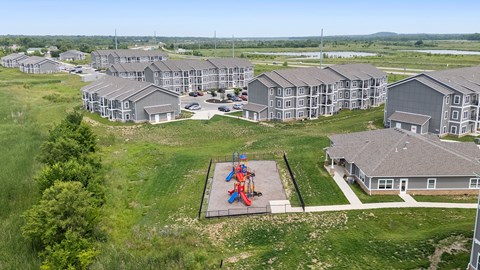 A playground with a slide and swings is surrounded by apartment buildings.