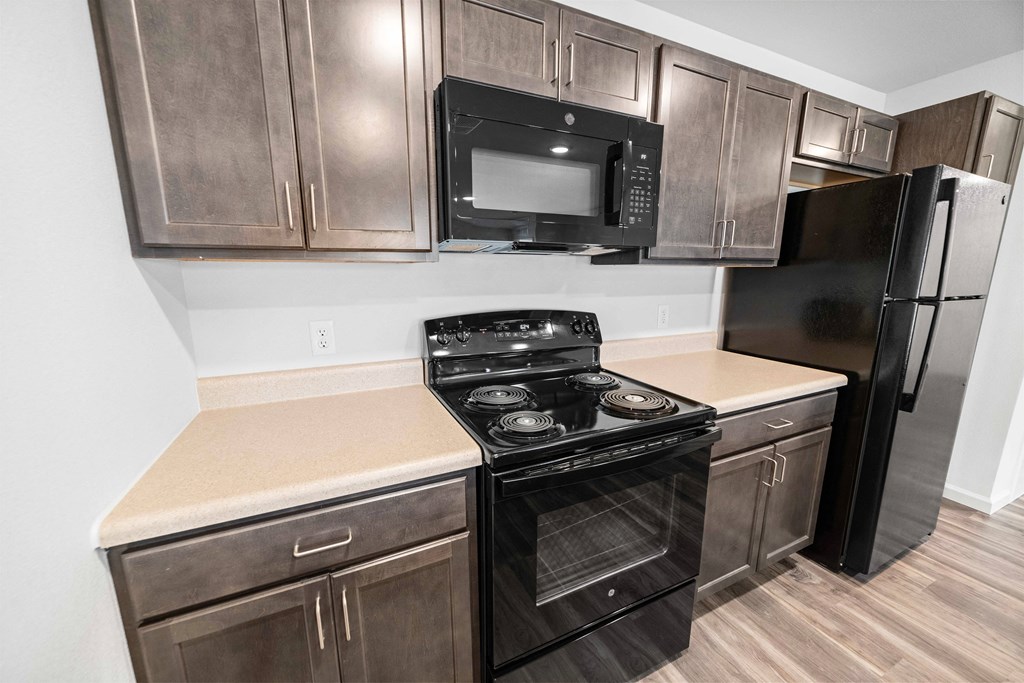 a kitchen with dark wood cabinets and black appliances  at Union at Wiley, Iowa, 52404