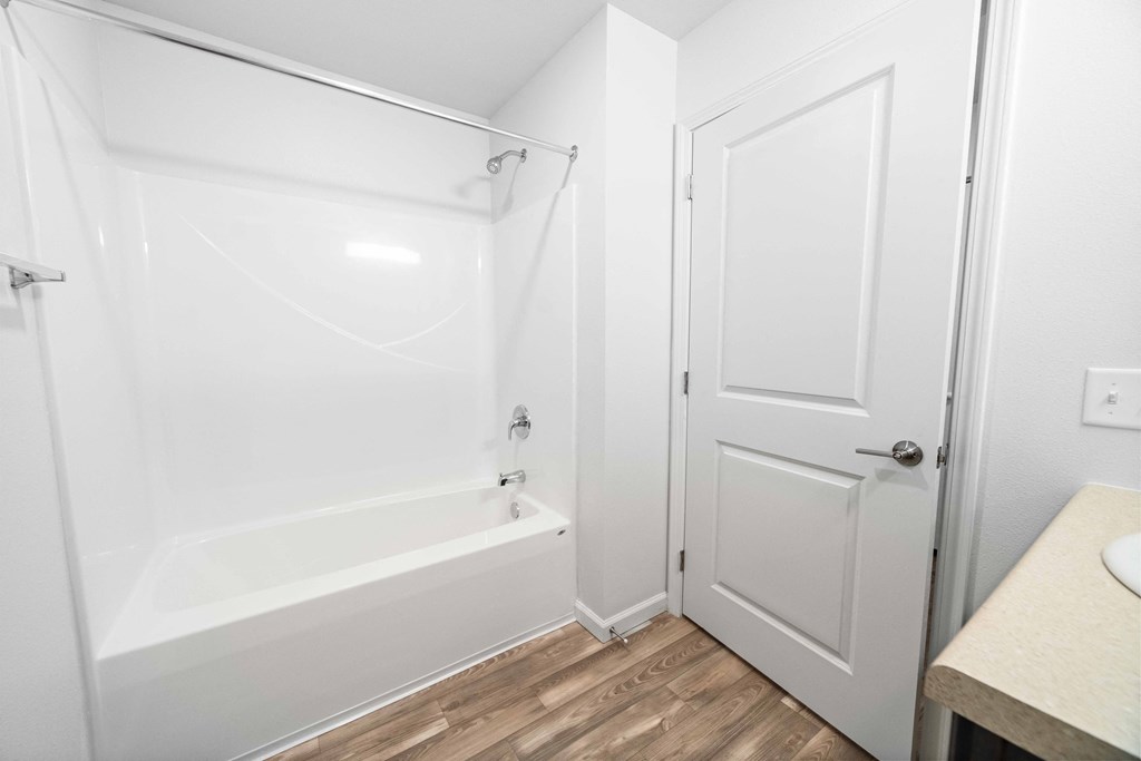 a bathroom with a white bathtub and a white door  at Union at Wiley, Cedar Rapids, Iowa