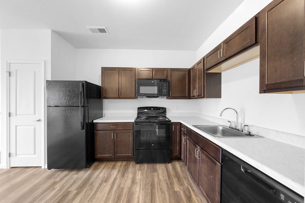 A kitchen with black appliances and brown cabinets. at Union at the Loop, Lawrence, KS, 66046