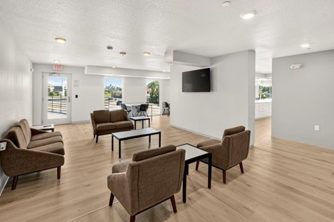 A living room with brown chairs and a black TV mounted on the wall.